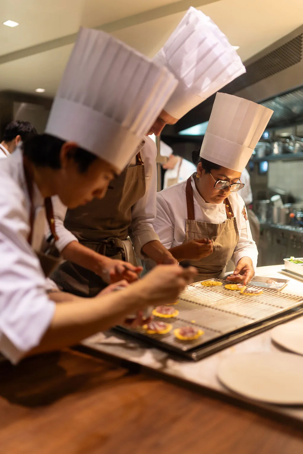 Chefs en toque dressant les assiettes dans la cuisine ouverte du Marsan à Paris