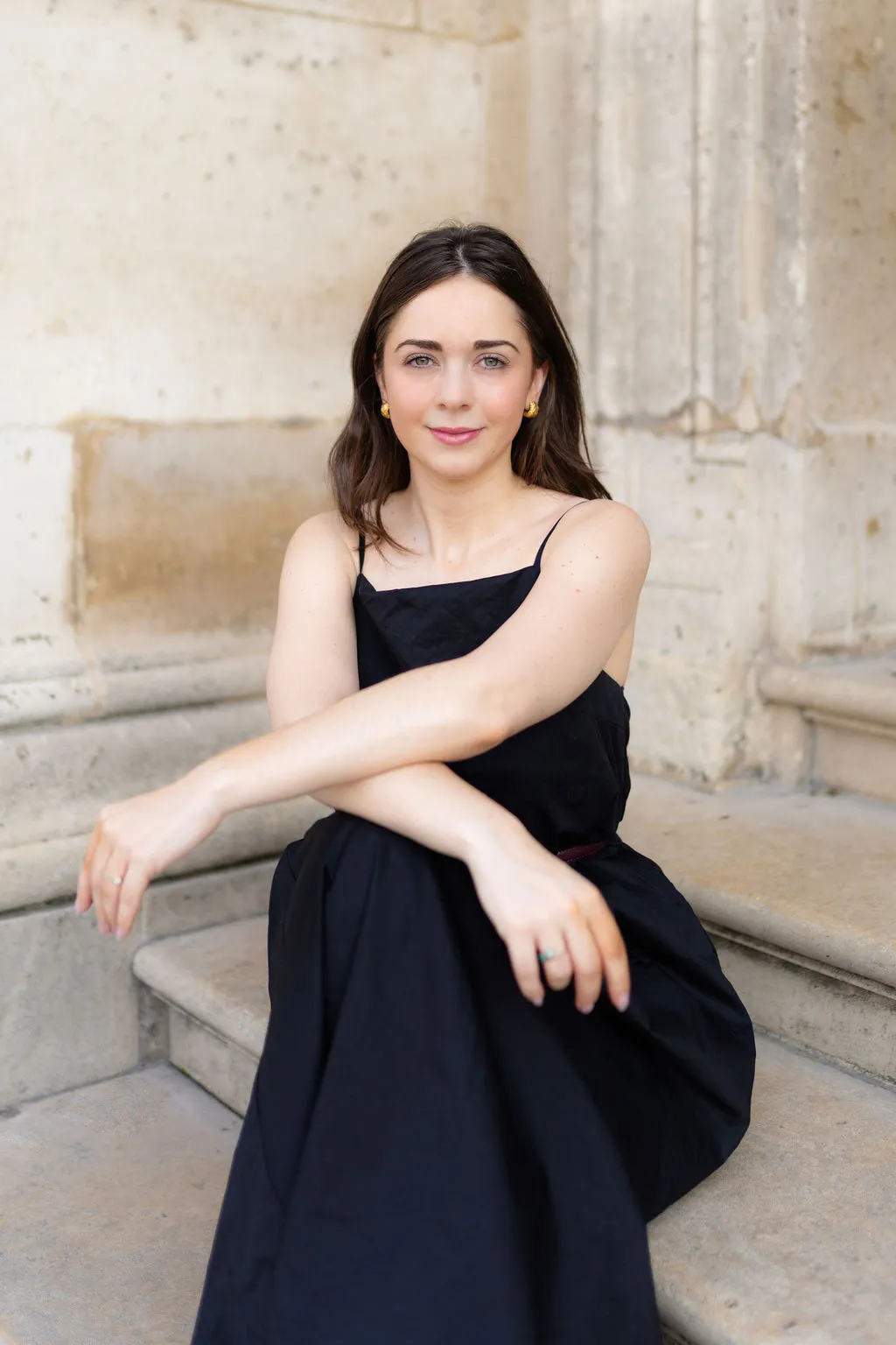 Portrait lifestyle d'une avocate assise sur les marches d'un bâtiment parisien